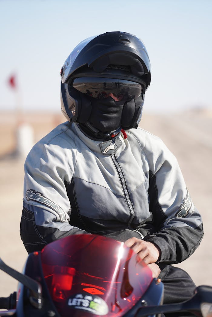 gallery-6 Biker with helmet on a motorcycle, posing in a desert setting under daylight.