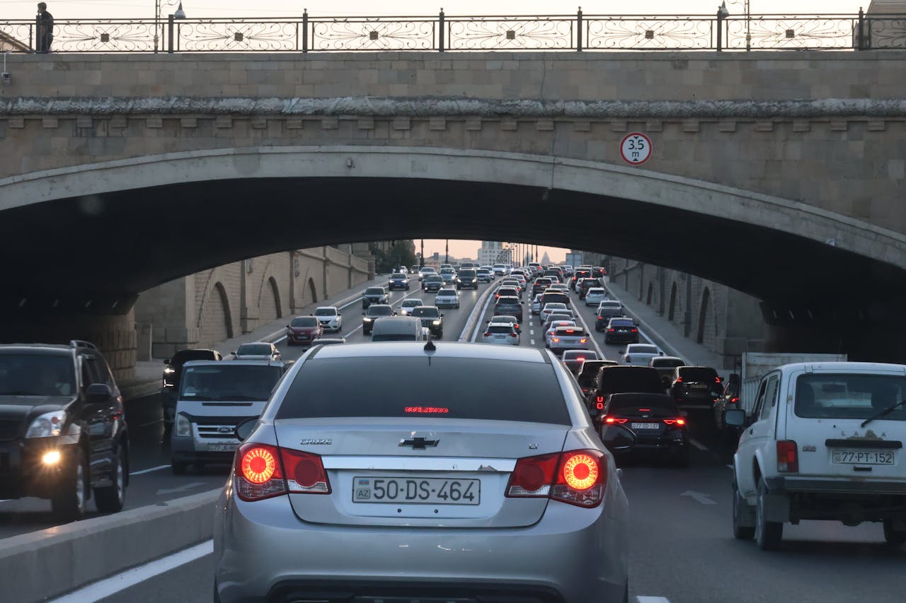 services-01 View of cars in a traffic jam under an arch bridge during twilight, capturing urban congestion.