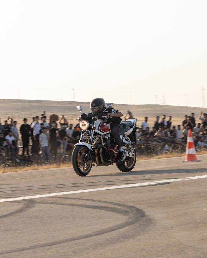 gallery-2 Motorcycle racer speeding on track with an eager crowd in the background during a sunny day event.
