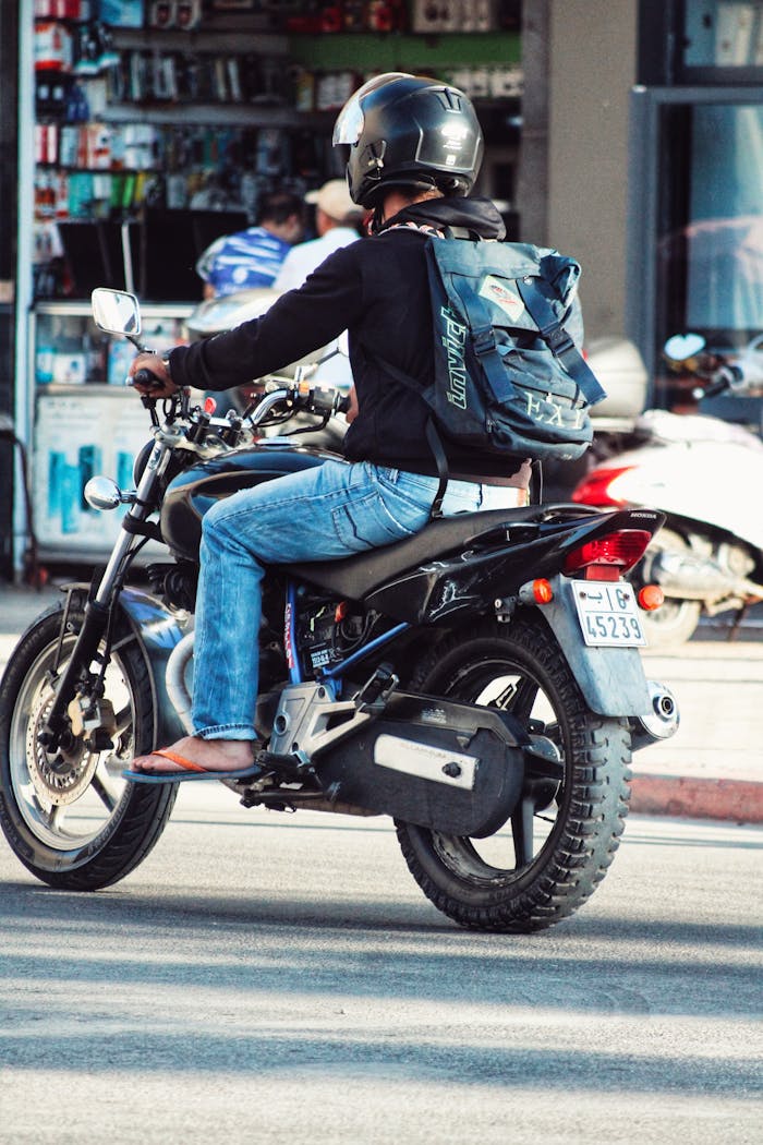 why-choose-us A motorcyclist riding in urban traffic, wearing a helmet and backpack.