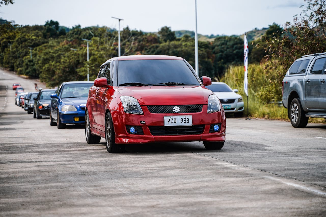 about-01 A vibrant red car leads a convoy on a countryside road in Mangatarem, Philippines.